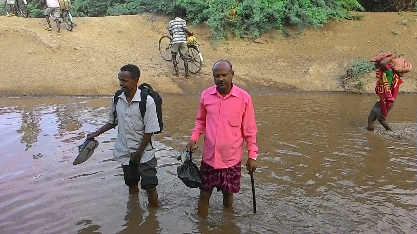 Missionaries crossing a river on the way to a low land village